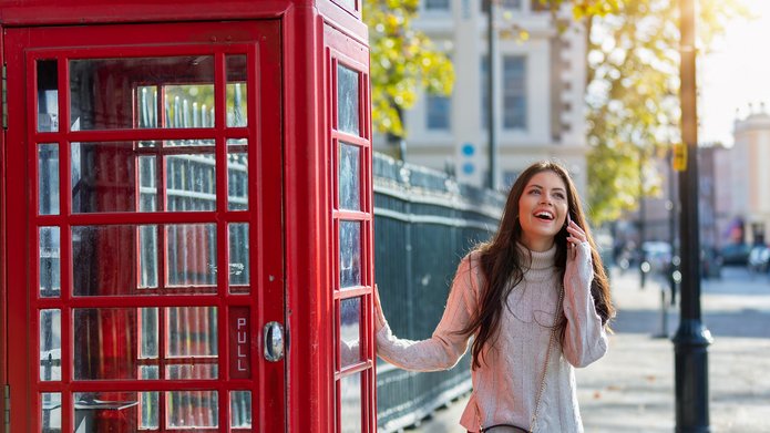 zdjęcie uśmiechniętej kobiety obok londyńskiej budki telefonicznej